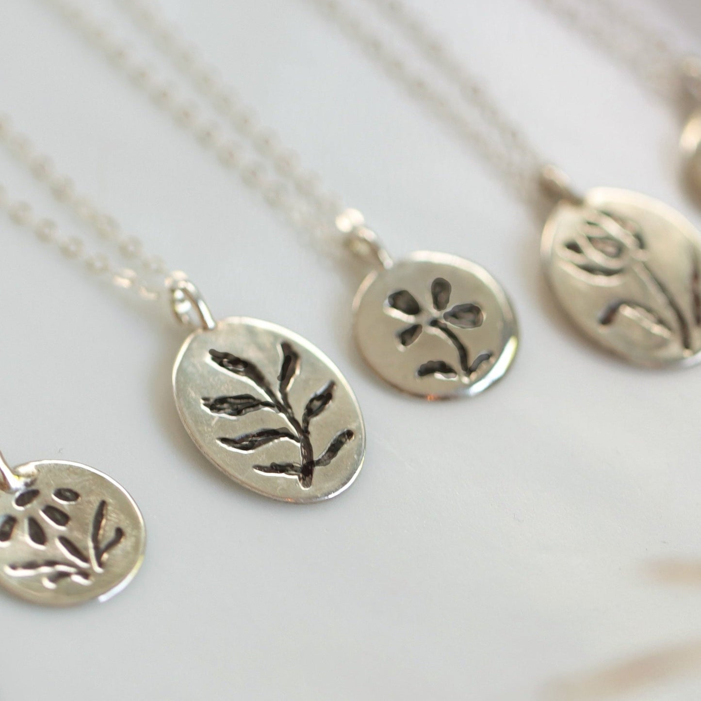 Silver necklaces with engraved pendants on a white background