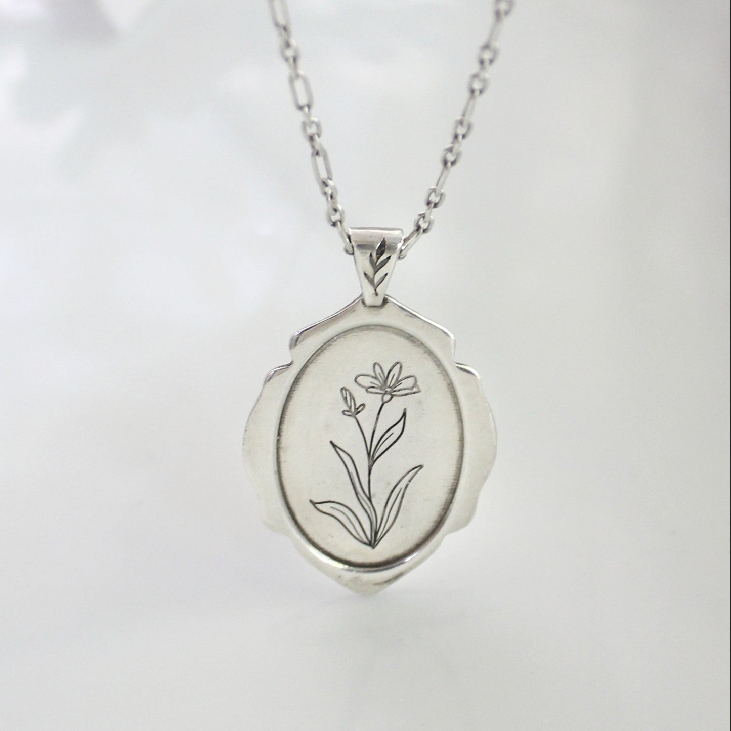 Silver locket with floral engraving on a white background