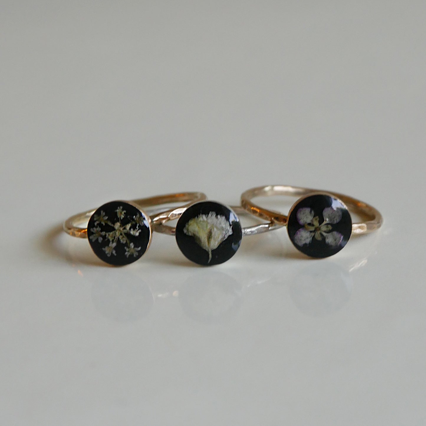 Three gold rings with black stones featuring floral designs on a light gray background