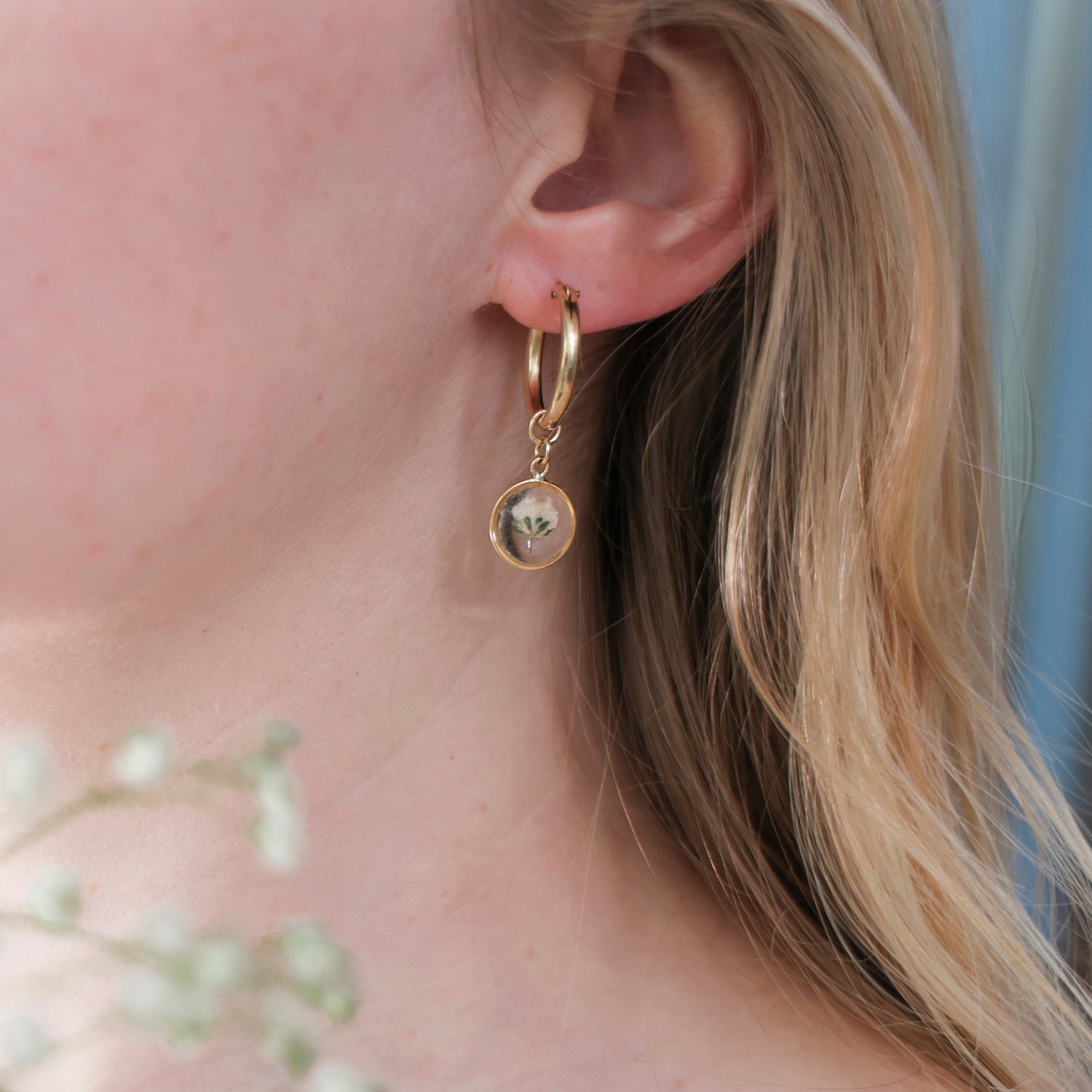 This image features a pair of elegant sun earrings, each adorned with a delicate Gypsophila flower. The earrings are crafted in a subtle gold color, enhancing their sophisticated appeal.