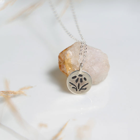 Silver necklace with a pendant on a marble surface

