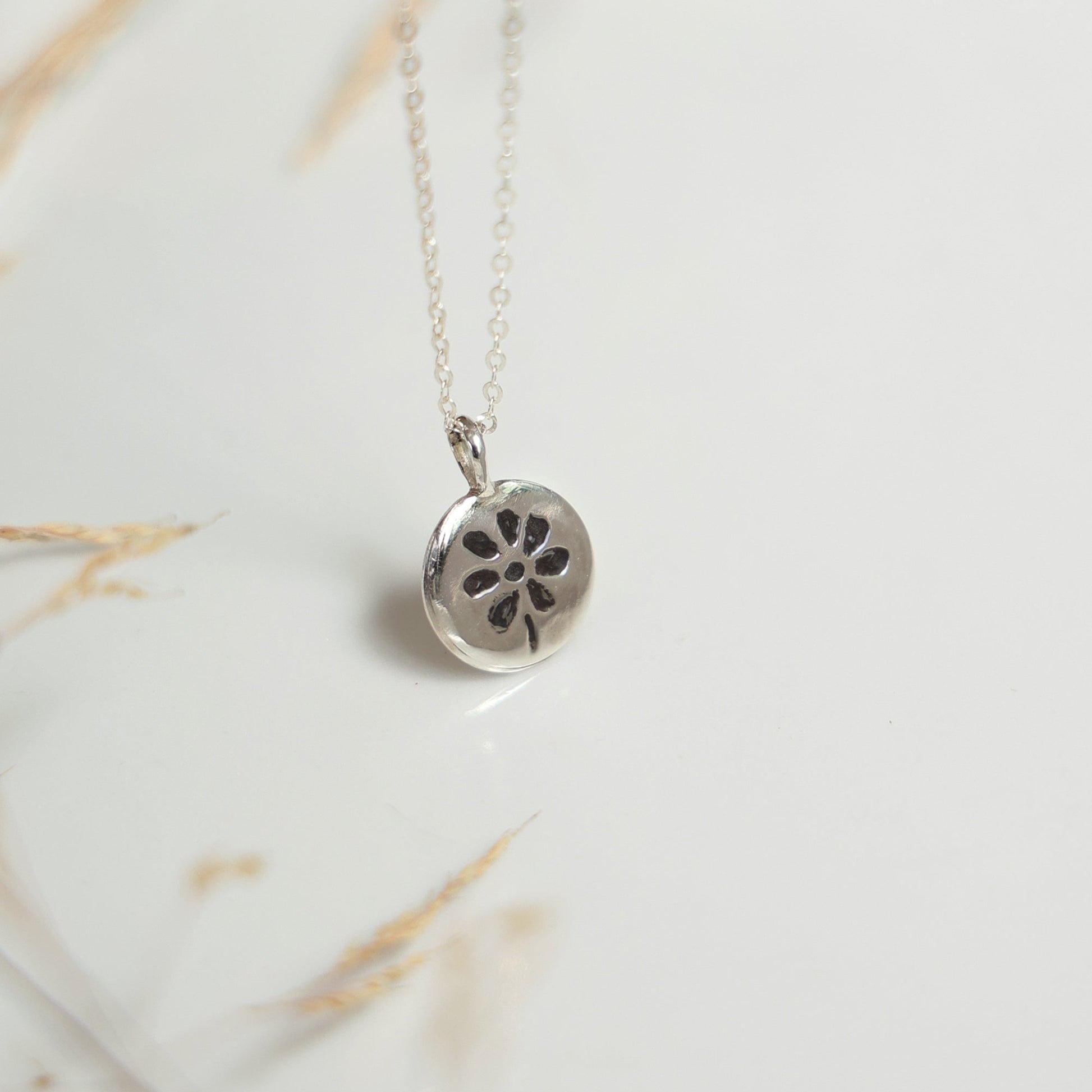 Silver necklace with a floral pendant on a marble surface