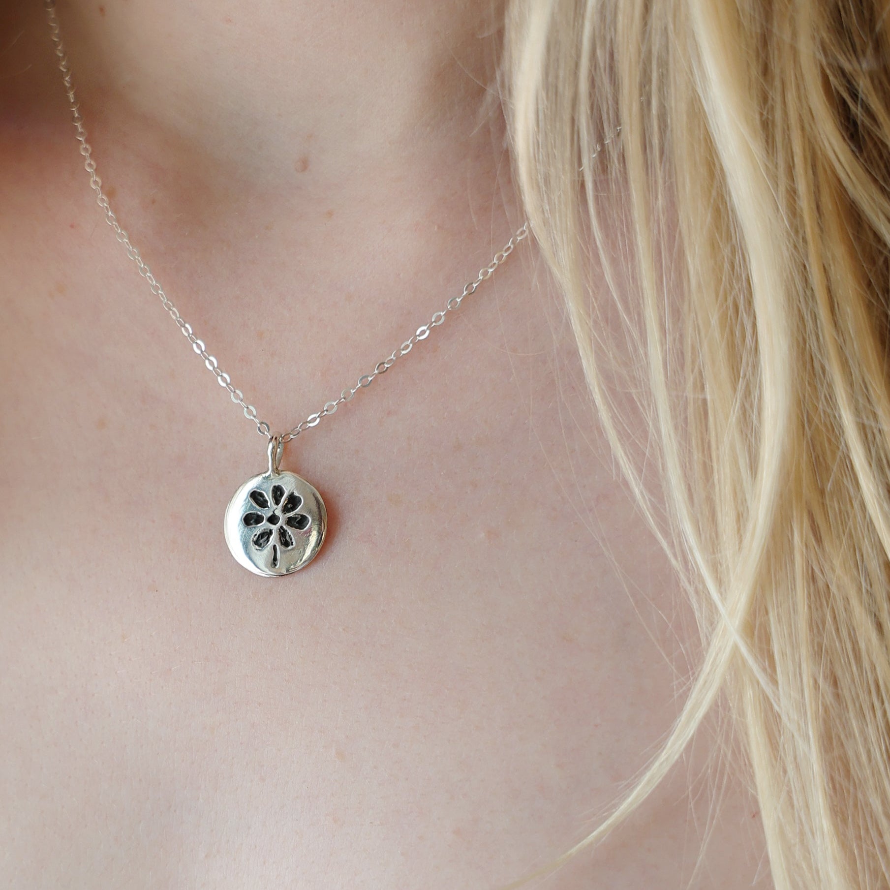 Silver necklace with a pendant worn by a person in a white garment