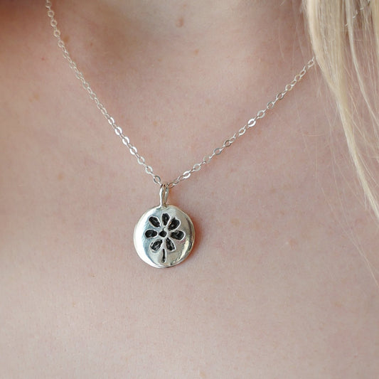 Silver necklace with a pendant worn by a person in a white garment