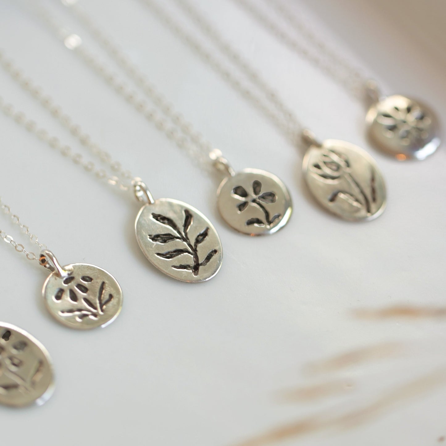 Silver necklaces with engraved pendants on a white background