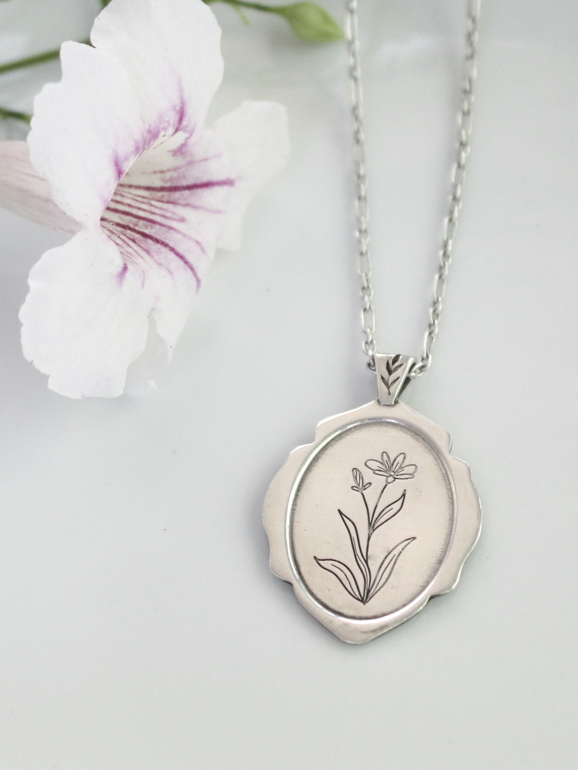 Silver locket with floral engraving on a light background