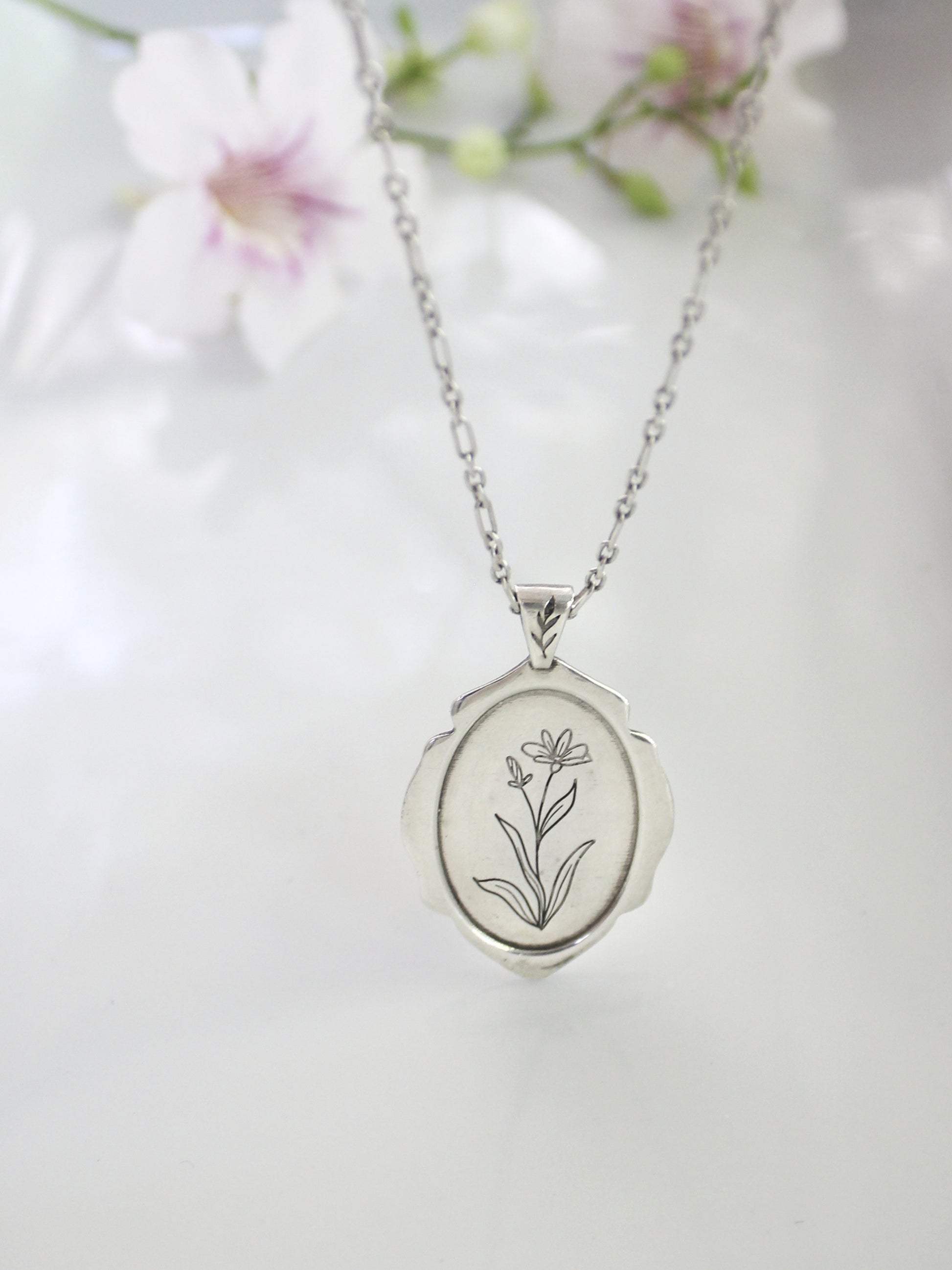 Silver locket with floral engraving on a white background