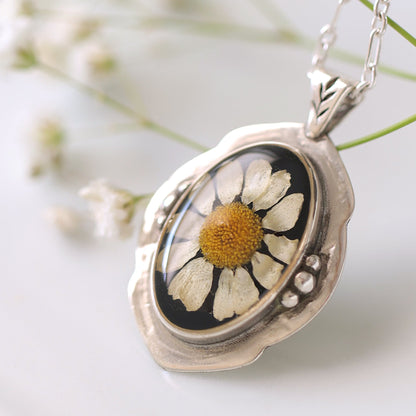Silver locket with a pressed flower pendant on a white background