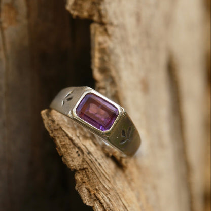 Silver ring with a purple gemstone on a wooden surface