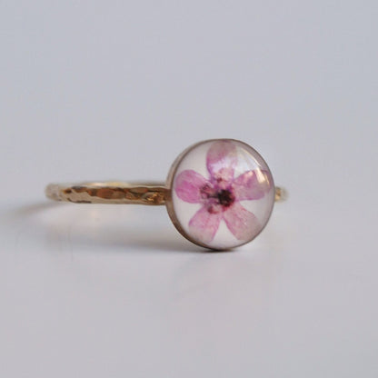 Ring with a pink flower design on a light gray background