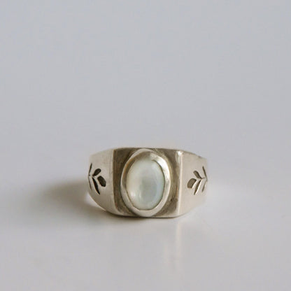 Silver ring with a central gemstone on a light gray background