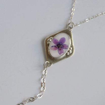 Necklace with a pendant featuring a purple flower on a white background