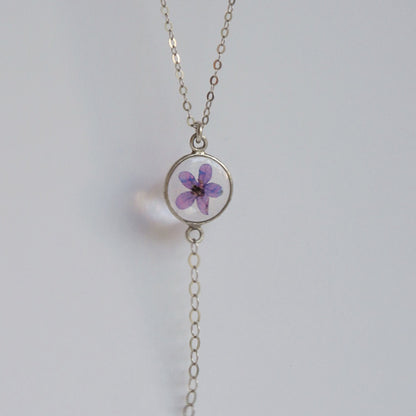 Necklace with a round pendant featuring a purple flower on a light gray background