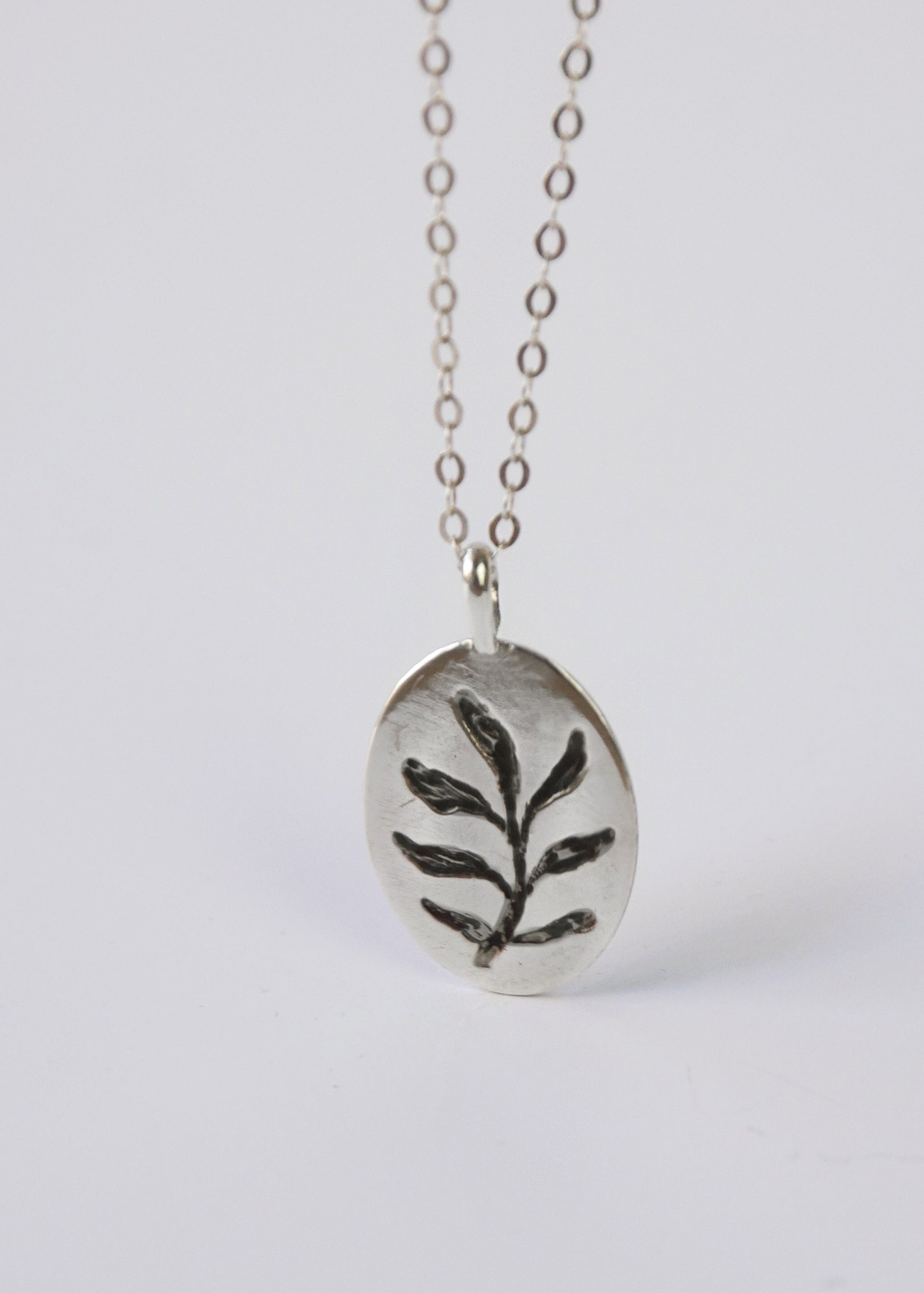 Silver necklace with a leaf pendant on a white background