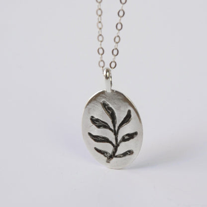 Silver necklace with a leaf pendant on a white background