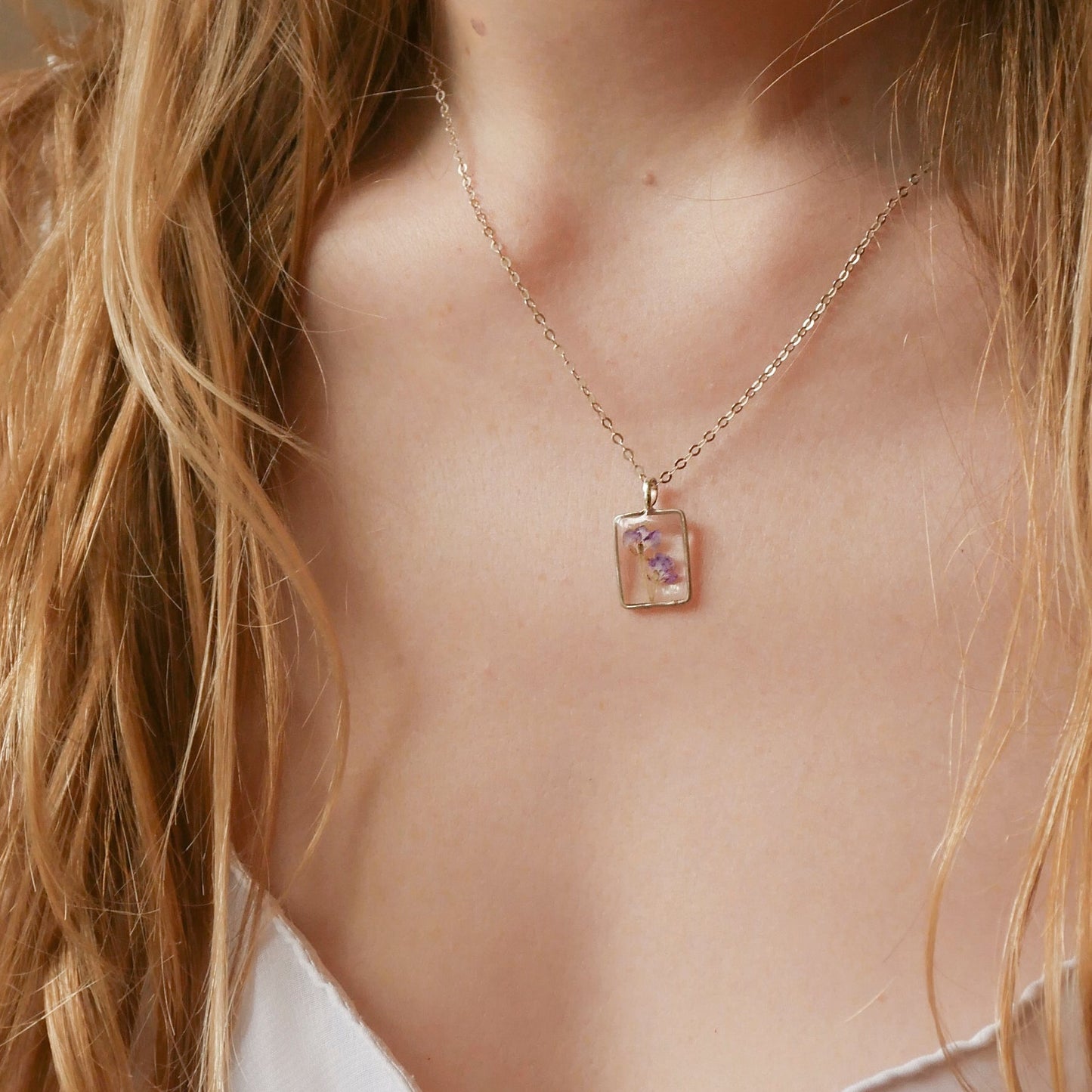 Necklace with a pendant worn by a person with long blonde hair.