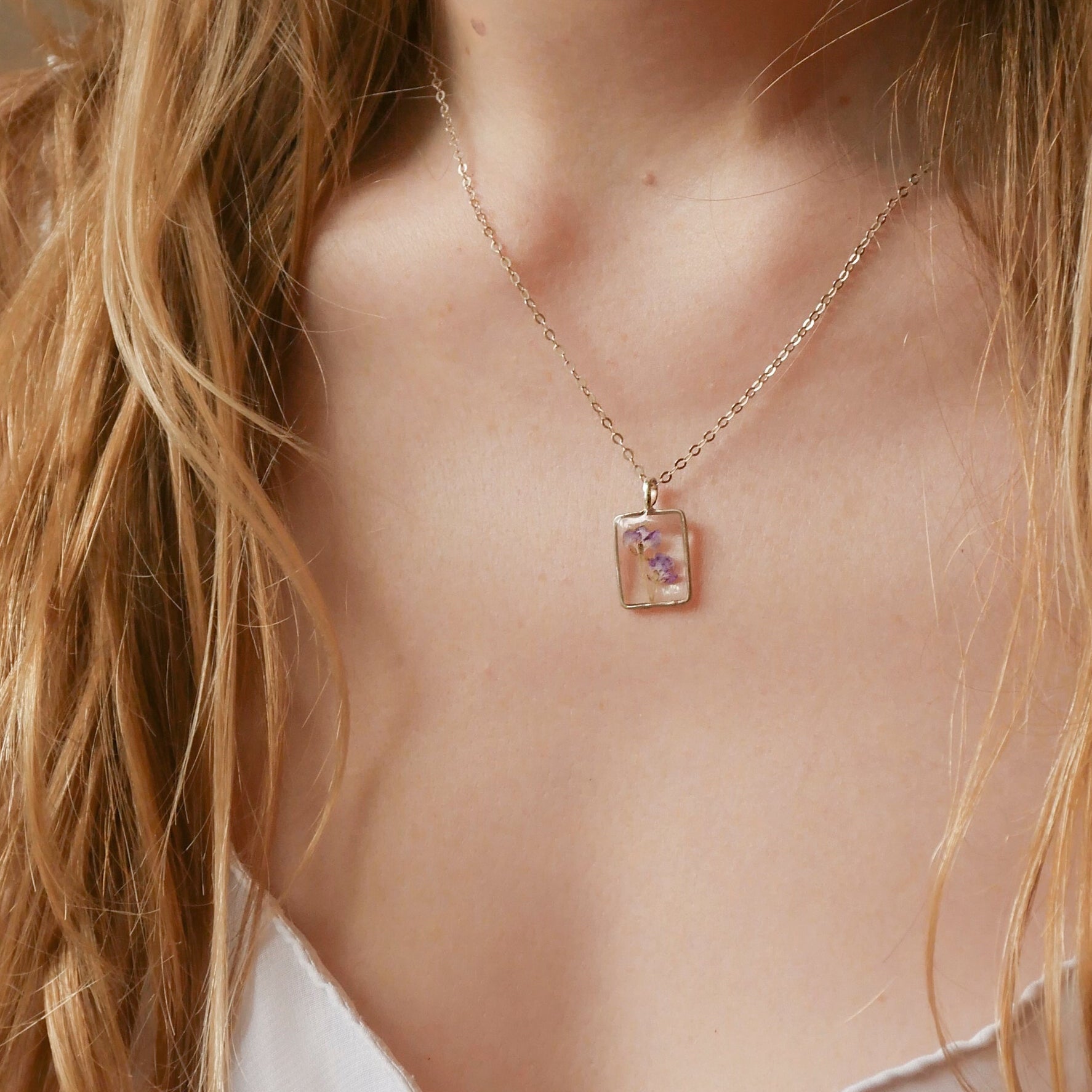 Necklace with a pendant worn by a person with long blonde hair.
