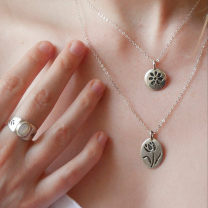 Silver necklaces with pendants on a person wearing a white top.