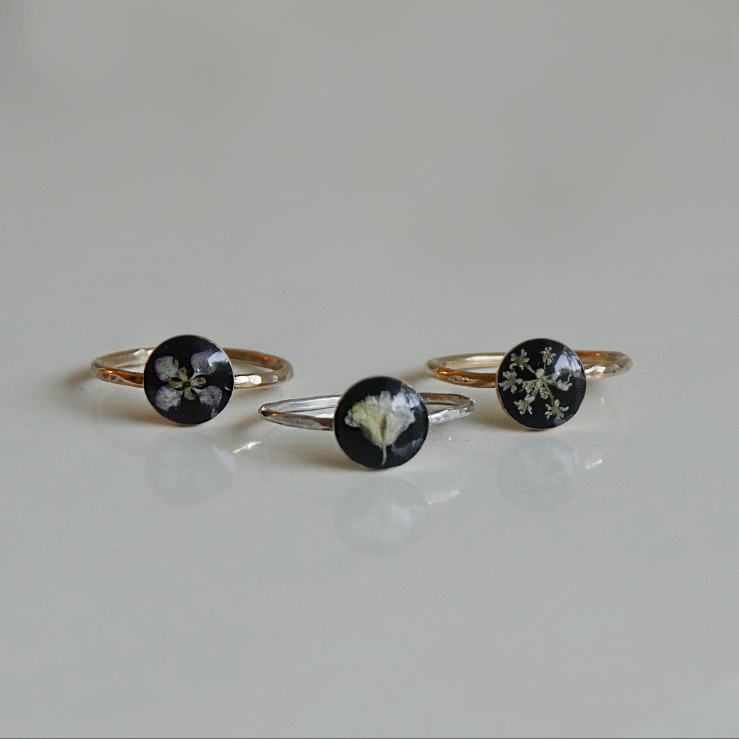 Three floral ring designs on a light gray background