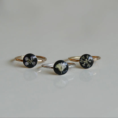 Three floral ring designs on a light gray background