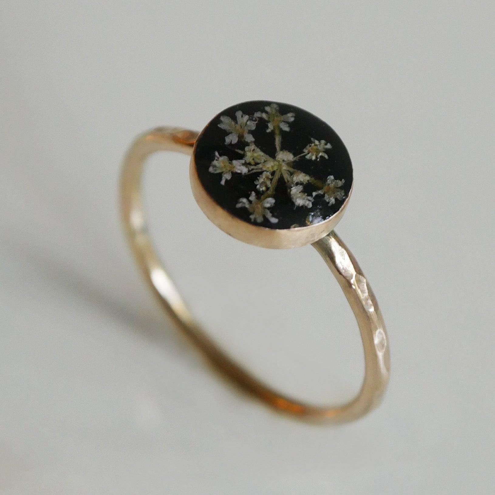 Gold ring with a black stone and floral design on a light gray background