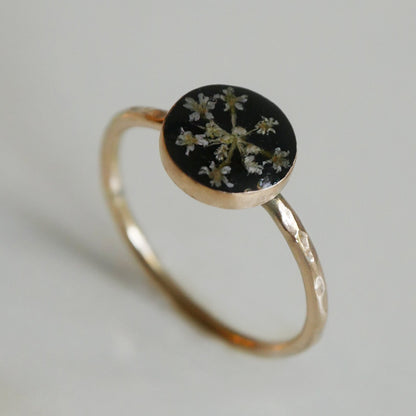 Gold ring with a black stone and floral design on a light gray background