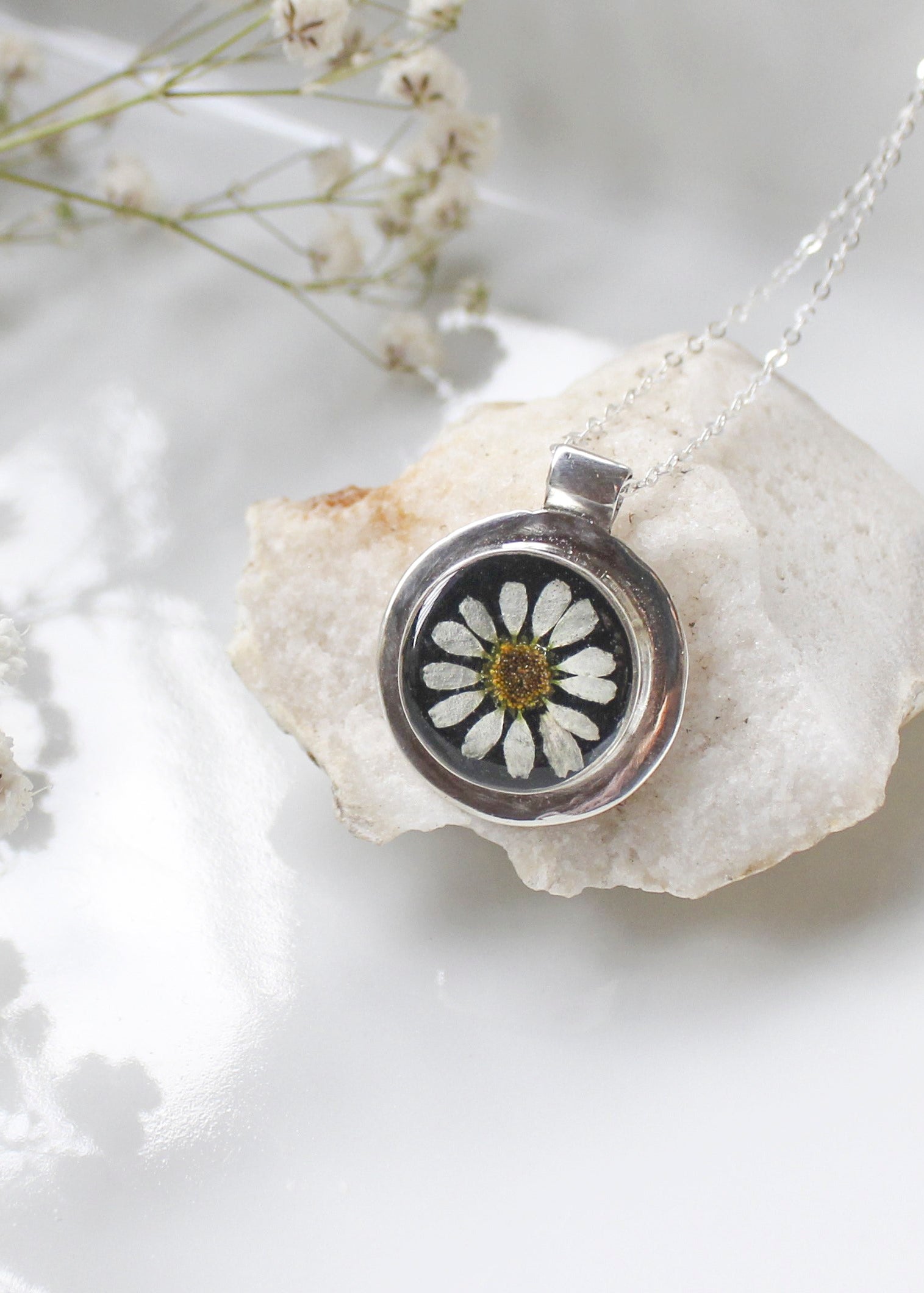 Silver pendant with a pressed flower on a white stone